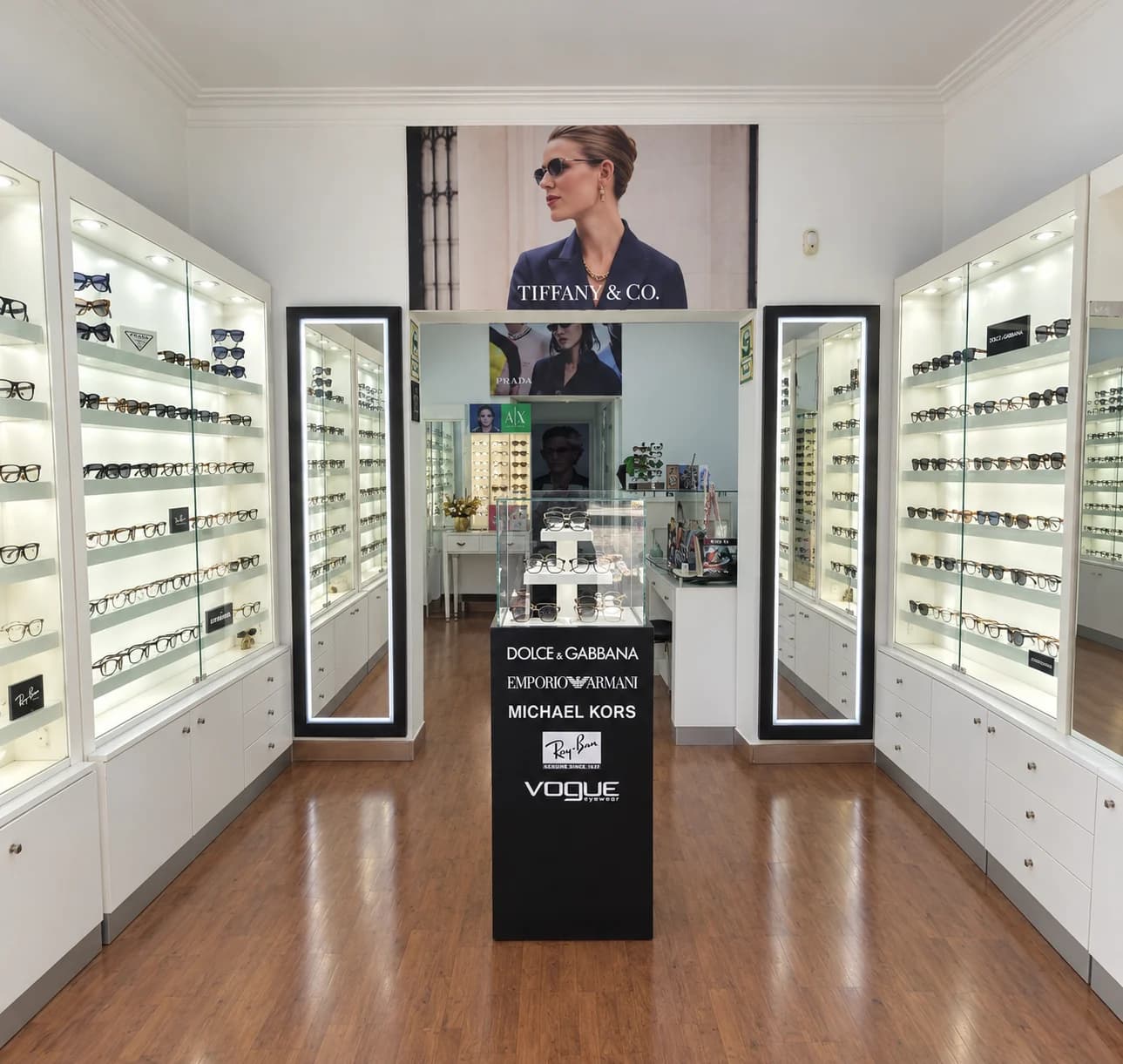 Interior de la tienda de Optical Visión y Moda: vitrinas iluminadas con lentes a ambos lados, piso de madera y un exhibidor de marcas al centro